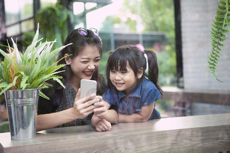 人们青年药片正在家中客厅寻找智能电话屏幕的年青亚洲小妇幼女和儿童图片