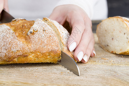 保持食物面粉女人把一利刃切成团面包的刀子在切餐板上早煮饭切面包手图片
