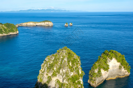 洛基天空热带海岸附近的小落基岩岛海洋地平线上布满丛林山脉和云雾的小岩岛支撑图片