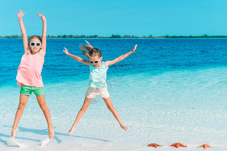 加勒比海滨女儿夏日度假时海滩上可爱的小女孩与绿海和白沙一起在滩上玩得开心美丽的小女孩在海滩上很快乐图片