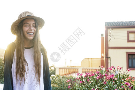 街道年轻快乐的青少旅行女孩穿着暑期服装和帽子站在街外露天看摄影机时站立在街上露齿的梦幻般图片