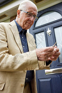 健忘患有早期痴呆症并试图寻找正确门钥匙的老年人在外屋寻找正确的门键房子男人图片