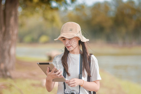 户外手拿平板电脑和相机旅游的女性图片