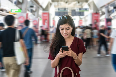 人使用BTSSkytrain铁路或MRT地的智能移动电话在大城市旅行生活方式和交通概念中搭乘便衣亚洲女客车游泰国图片