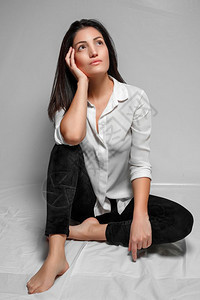 女时髦的绑腿身着白衬衫和黑色长腿的头发女人坐在白色背景上图片