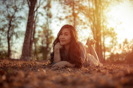 年轻的亚洲女人在秋天公园的摄像头面前摆姿势可爱的微笑相机图片