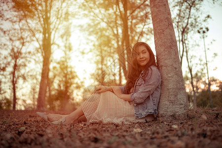 可爱的橙美丽年轻亚洲女人在秋天公园的摄像头面前摆姿势图片
