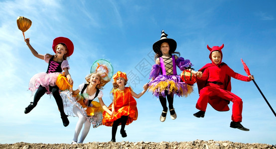 愉快五个乐儿童一起在蓝天和魔鬼万圣节装饰品中玩弄诡计或治疗对待包图片