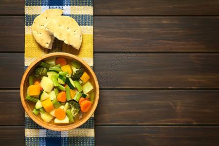 素食主义者木制的由Zucchini绿豆胡萝卜椰菜西兰花马铃薯和南瓜制成的木碗蔬菜汤在厨房毛巾上贴着包子的土豆和南瓜以天然光照黑木图片