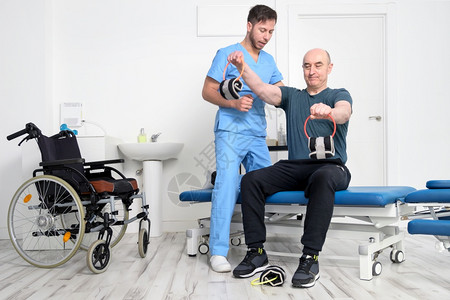 残疾男子用哑铃做恢复运动患有Ataxy的人在恢复支持治疗理保健系统中高质量照片的人在恢复支持治疗理保健系统中男人轮椅医院图片