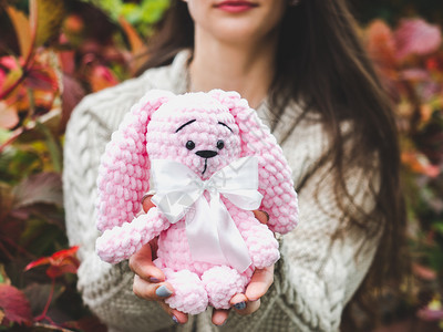 兔子毛衣可爱的年轻女人手握着一个填充玩具可爱的年轻女人手握着一个填充玩具坐着图片
