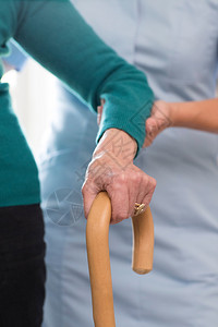 老年女与背景护理工作者一起行走时手握社会的高级过程图片