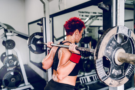 红发女郎在健身房后背部做蹲下腿训练用巴铃做客厅钟声看身体锻炼是否健康肌肉发达女士头图片