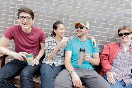 四位朋友在座笑和饮用咖啡积极的随意男图片