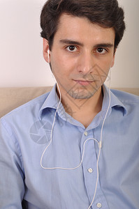 衬衫男人耳机在沙发上听音乐的有吸引力年轻人图片