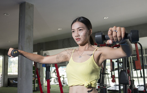 积极的亚洲运动女在健身房用哑铃黑发保持图片
