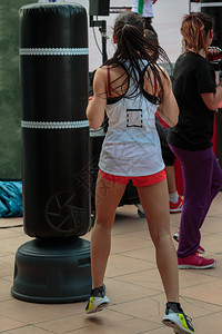 斗争健身房女穿短裤的年轻女孩和白色最合适的白拳击袋竞技游戏图片