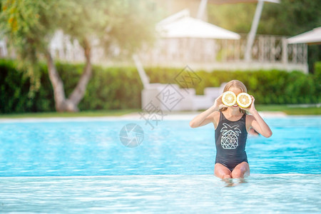 小女孩在游泳池里拿柠檬挡脸图片
