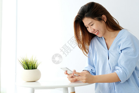 社会的年轻亚洲女使用智能手机微笑快乐和放松的情绪在白室背景中电话上的人生活方式屏幕数字的图片