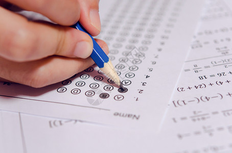 学生手握铅笔在答题单和数学问上写有选择的作考试学校的生进行测以及讲师学生们查看图片