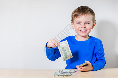 愉快有钱的乐孩子小商人一堆美元百钞票在男孩手里有钱的快乐孩子小商人一堆美元百钞票保持商业图片