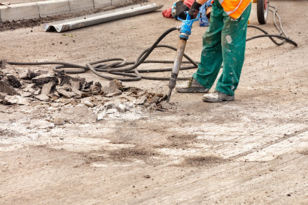 粉碎一名身穿绿衣的公路工人在夏季日用一个充气手推土机在路上解开旧沥青并在路边用一台充气手推土机拆散旧沥青工作维修图片