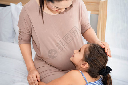女儿拥抱母亲倾听在母腹中的孩子声音图片