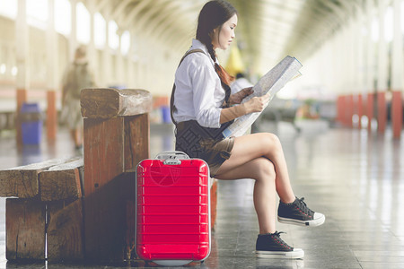 女在火车站旅行时亚洲孕妇坐在长椅上看和红色手提箱的皮Holiday旅行概念父母乘客图片