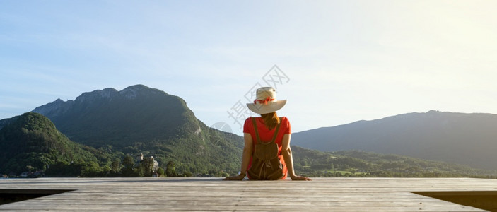 帽子穿着跟鞋和红礼服的女孩在湖边码头上看山穿着鞋子生活观的概念假期水图片