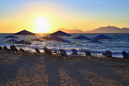 日光浴床景观假期暑和旅行的美景概念在日落时海边滩有阳光和雨伞天空图片