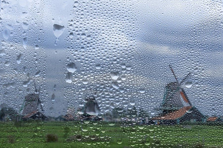 荷兰在雨天中ZaanseSchans的老荷兰风车通过一个有雨滴的窗口浏览荷兰旧风车窗从雨通向荷兰的旧风车窗湿力量旅游图片