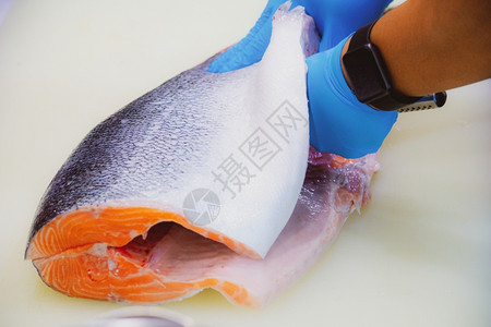 文化营养商业的切沙门鱼片主厨切开新鲜生鲑鱼片餐桌上的剪板有一把尖利刀手紧图片