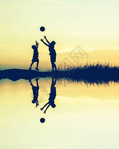 大约男孩在日落时玩橄榄足球采用水反射环影概念爱跳舞图片