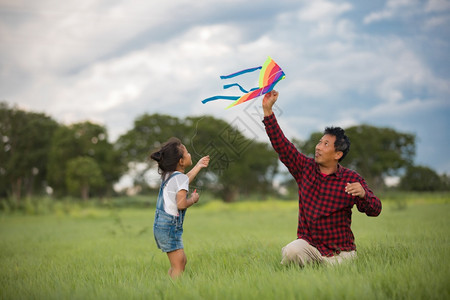 场地亚洲女孩和父亲带着风筝跑来去夏天在草地上快乐的亚洲女孩和父亲自然乐趣图片