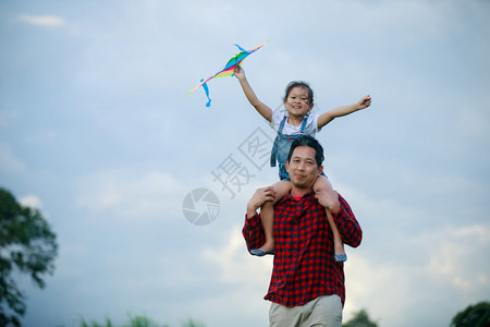 亚洲女孩和父亲带着风筝跑来去夏天在草地上快乐的亚洲女孩和父亲人白种们图片