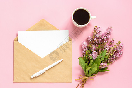 手工艺美丽的空一束粉红色花朵带有白色空卡的信封和粉红色背景的咖啡杯贺卡平躺模型概念早上好或妇女节粉红色的花束带有白色空卡的信封和图片