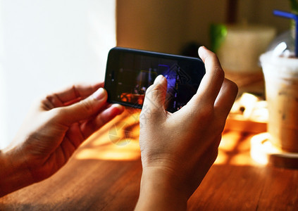 复制女士使用智能电话的人在木板上拍摄咖啡的照片手指图片