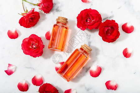 玻璃瓶和小红玫瑰中的香水配有花瓣按摩芳香疗法和有机化妆品概念大理石花的液体图片