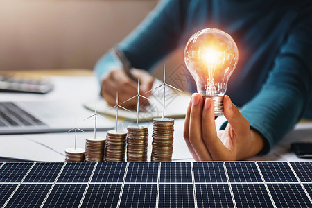 灵感力量金融的拥有硬币涡轮和太阳能电池板概念节省能源和财务会计的灯泡带有硬币涡轮的女商人图片