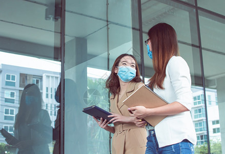 戴着口罩在室外和同事聊天的女性图片