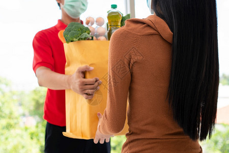 新鲜的脸应用程序来自超市的亚洲送货员身戴面罩持有一袋新鲜食品蔬菜和水果供家里顾客使用特快杂货服务和新生活方式概念服务与新生活方式图片