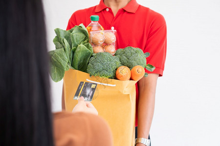 一种商业来自超市的亚洲送货员身戴面罩持有一袋新鲜食品蔬菜和水果供家里顾客使用特快杂货服务和新生活方式概念服务与新生活方式快乐的图片