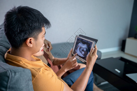 孕妇和丈夫在家中沙发上看婴儿的超声扫描背景图片