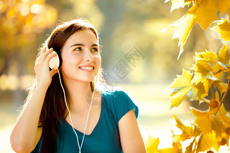 青少年在秋天的优美节日以耳语聆听音乐节目时普拉坦公园图片