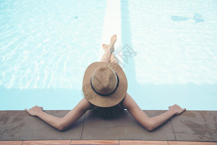 泳装女人戴着大帽子在泳池放松图片