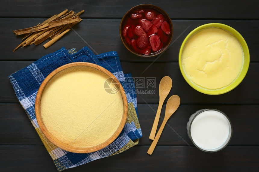水平的营养木质碗中原生血素的涂片配有Semolina布丁牛奶杯一碗草莓甘油和肉桂棒用天然光照在黑木上勺子图片