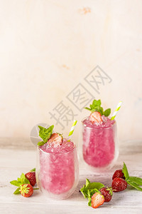 白色的甜盛装草莓和冰块的新鲜夏季鸡尾酒在浅粉红背景上喝杯草莓苏打汽水浆果背景图片