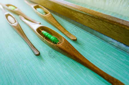 梭布垭石林古老的织机上梭工具中绿色纱线纺织物编使用传统布机和梭进行编织泰国纺或布料生产绿色手工布家庭织背景