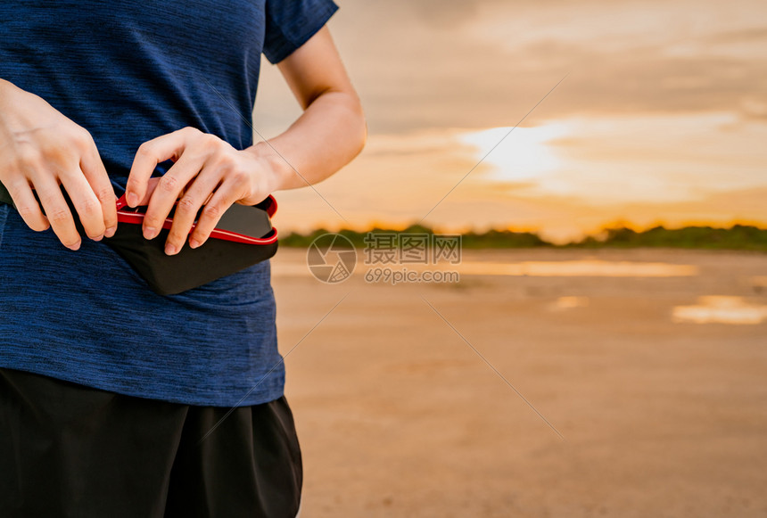 女士夏天电话年轻的亚裔女跑者将智能手机放在腰包中然后上午进行心操锻炼前先用腰袋装有智能手机然后在外门健身运动康生活方式慢跑和马拉图片