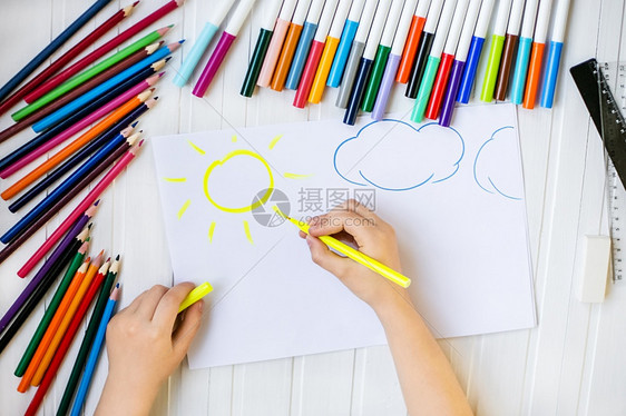 女孩自我表达童子手用彩色铅笔涂在木制桌上一张白纸童子手用彩色铅笔画在纸上屋图片